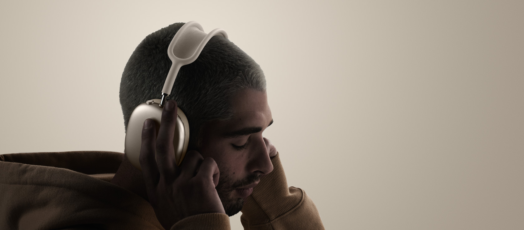 Imagem lateral de uma pessoa usando os fones de ouvido AirPods Max 2 e tocando nas almofadas