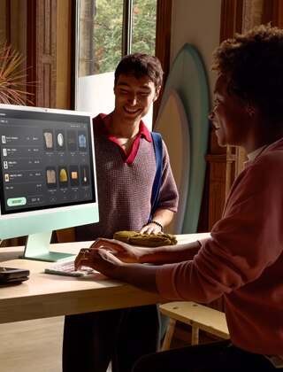 Duas pessoas em uma sala bem iluminada vendo produtos na tela de vidro nano-texture do iMac.