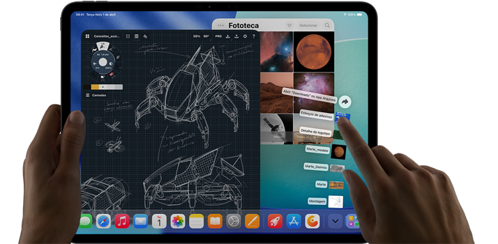 iPad Pro na cor preto-espacial. A mão esquerda segura o aparelho, e a mão direita aponta e gesticula para manipular várias janelas abertas de apps. Um app de desenho mostra esboços de projetos mecânicos, a fototeca mostra imagens de planetas e do espaço, e a pasta de downloads exibe arquivos em formato de leque.