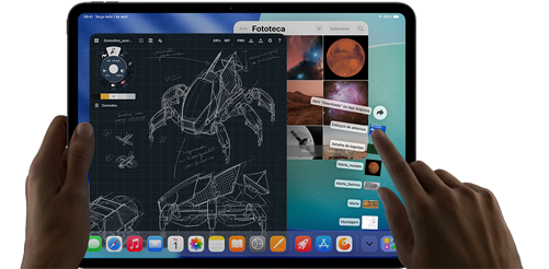 iPad Pro na cor preto-espacial. A mão esquerda segura o aparelho, e a mão direita aponta e gesticula para manipular várias janelas abertas de apps. Um app de desenho mostra esboços de projetos mecânicos, a fototeca mostra imagens de planetas e do espaço, e a pasta de downloads exibe arquivos em formato de leque.