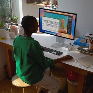 Uma pessoa usando um Mac mini e um monitor para trabalhar em apps com uma tela colorida