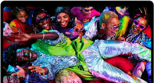 A tela colorida de um MacBook Pro mostra uma pessoa passando por cima de uma multidão em uma festa, destacando a tela Liquid Retina XDR em cores vibrantes