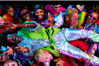 A tela colorida de um MacBook Pro mostra uma pessoa passando por cima de uma multidão em uma festa, destacando a tela Liquid Retina XDR em cores vibrantes